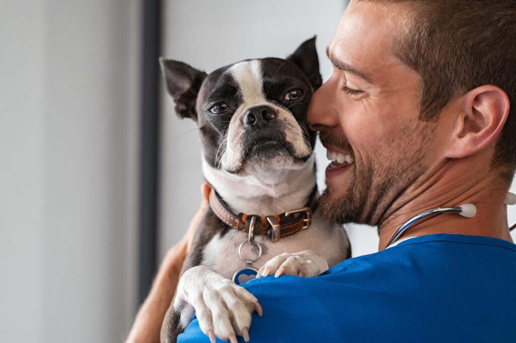 A Man Carrying A Small Dog